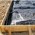 This Texas homes uses a slab foundation including a 4-in.-thick post-tensioned monolithic slab with turned-down edges poured over a 6-mil polyethylene vapor barrier and capillary break; slab edge insulation is not used due to termite risk.
