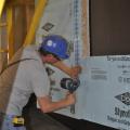 The tape is applied with even pressure to ensure the seams in the rigid foam sheathing are air sealed on this manufactured home.