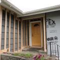 Ledger board, metal brackets, and vertical 2x4s have been installed in preparation for exterior spray foam in this retrofit exterior wall insulation technique