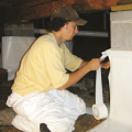 Right - A technician wraps the foundation piers with a vapor retarder in preparation for laying vapor retarder over the floor of this crawlspace. 