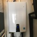 This wall-mounted high-efficiency condensing gas tankless water heater has PVC vent pipes and insulated water pipes