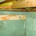 Polyethylene is being attached to the crawlspace floor and walls with plywood furring strips