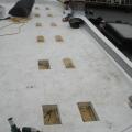 Roofing membrane is installed over polyisocyanurate rigid foam insulation and insulation cover board that has been cut to fit around locations for blocking for the PV system rack
