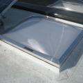 Strips of roofing membrane are used to flash around a skylight on a flat roof retrofit