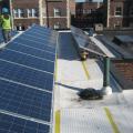 The retrofitted flat roof has PV panels and walking mats installed over the roofing membrane