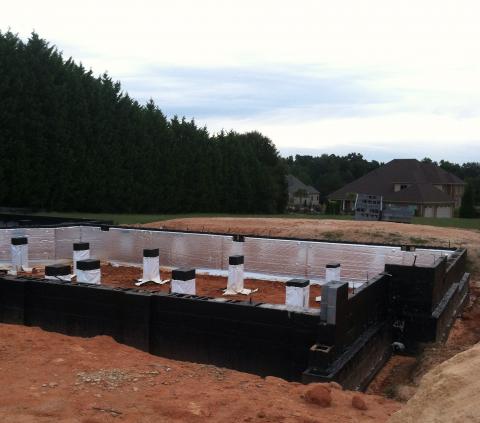 A paint-on waterproofing covers the exterior and tops of the concrete block foundation walls and piers to block moisture moving up through the concrete, while foil-faced R-13 insulation lines the inside surface of the exterior walls.