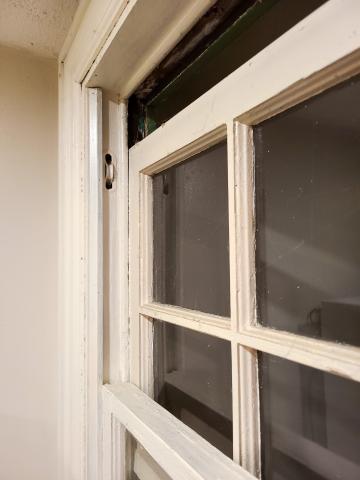 The pulleys in this old window frame were once used for counterbalancing weights to help raise and lower the window; this window can be restored with new pulley ropes or the weight pockets can be insulated with caulk and rigid insulation.
