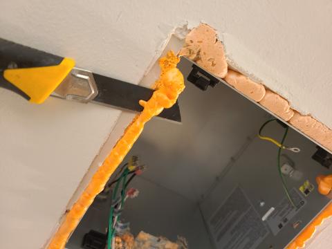 After spray foam dries, a utility knife can be used to carefully trim excess foam around the exhaust fan housing