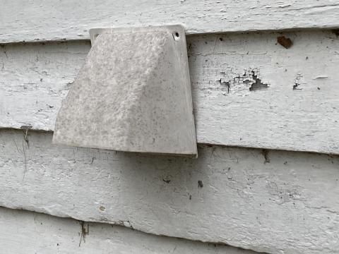 This hood covers an exhaust vent for a bath fan exterior vent; this hood is improperly installed and the top does not lap under the siding so water can easily get behind it