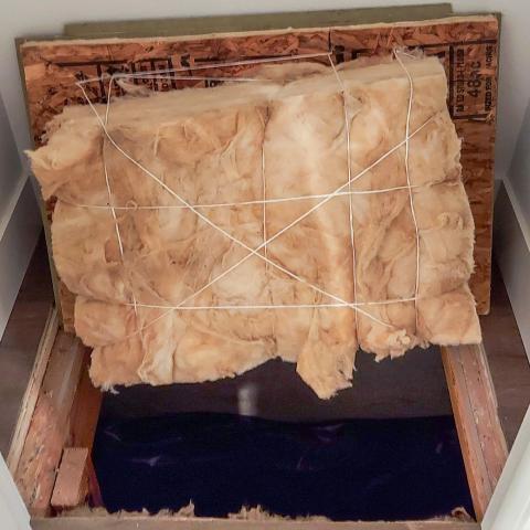 Batt insulation has been attached to this crawlspace hatch cover using twine and heavy-duty staples.
