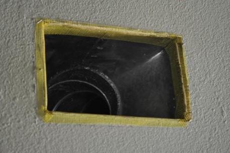 Fiberglass mesh tape is installed around a duct boot in preparation for air-sealing the seams with mastic.