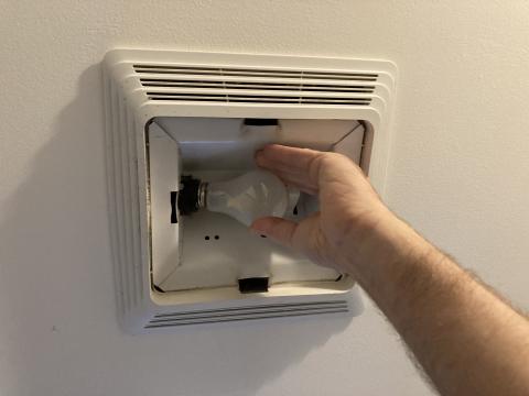 Remove the light bulb from the light fixture in the exhaust fan and clean the light housing with a vacuum brush attachment or cloth