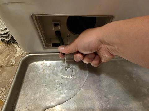 An old baking pan makes a handy container to catch water when you disconnect the emergency drain hose to clean the drain pump filter.