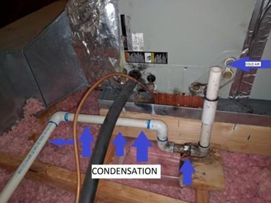 The uninsulated condensate line on this air conditioner located in an unconditioned attic is showing signs of condensation including wood staining at the elbow, discoloration at the joint, and liquid condensation on the pipe.