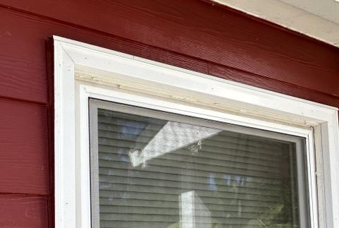 The metal head flashing over the window trim angles out slightly to provide a drip edge so rain water will drop away from the window instead of rolling down onto the window trim.
