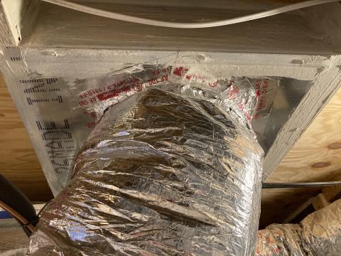 The large hole that was cut in the subfloor penetration for this HVAC duct has been air-sealed using sheet metal, mastic, and metal tape.