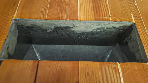 The seam between this duct register and the wood flooring is sealed with caulk to prevent air leakage into the house from the crawlspace below.
