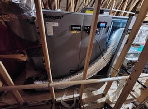 A duct test fan is set up for whole duct system testing with attachment to the central duct system inside the ERV cabinet