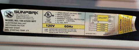 The electronic ballast of a linear fluorescent fixture is typically a black rectangular box located near the center of the fixture