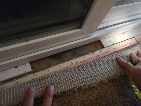 Pulling the carpet back reveals a large gap between the shims under the frame of this sliding glass door
