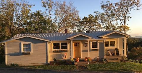 This home uses light-colored standard paints and finishes on siding and roofing materials to reduce cooling loads without adding material cost.