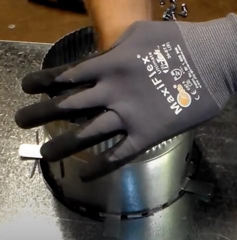 This duct take-off collar had become loose so the sheet metal tabs are being re-bent to make the collar more secure.