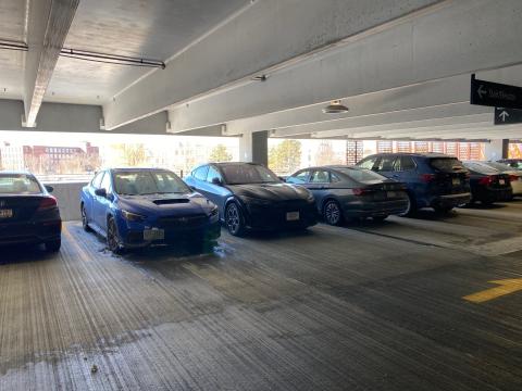 Mechanical exhaust is not required in this shared parking garage in a multistory multifamily building because the garage is not enclosed and can rely on natural air changes to reduce airborne contaminant concentration.