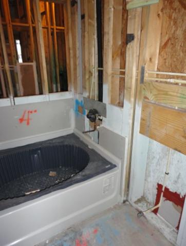 Gypsum board is installed behind the bathtub before the tub is installed and all seams are sealed