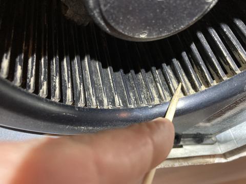 Scrape the debris from the sides of each fan blade on this bathroom exhaust fan.