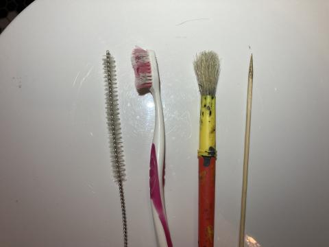Implements used to clean debris from exhaust fan blades.