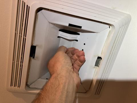 The nut holding the light housing in place in this combination exhaust fan/light can be unscrewed by hand