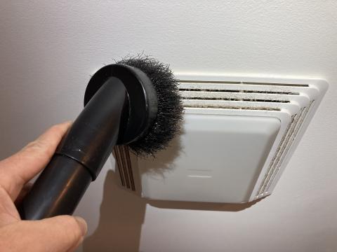 Use the brush attachment on your vacuum to remove dust and debris on the bathroom exhaust fan vents