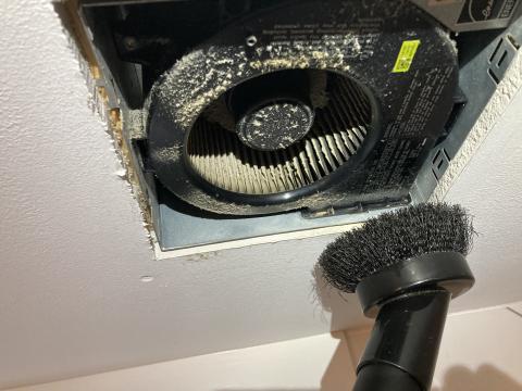 Use a vacuum brush attachment to clean the exhaust fan motor and blades