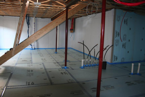 Right - Rigid foam insulation is taped at seams and installed over a drainage pad of aggregate to serve as a capillary break under the basement slab.