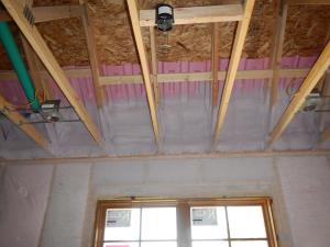 Spray foam insulates the top plates and air seals them to the ventilation baffles before ceiling drywall is installed.