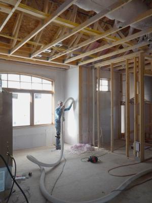 After spraying the 2x6 wall cavities with 2 inches (R-13) of closed-cell spray foam, the walls are covered with netting and an additional 3.5 inches of fiberglass (R-13) is blown in. 