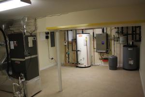 The mechanical room in the insulated basement houses the water heating equipment, including the storage tank for the solar thermal system and the wall-hung boiler as well as the air handler for the hydro coil and high-efficiency (16 SEER) air conditioner.