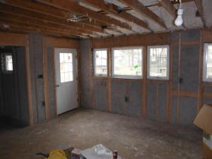 Drywall was removed and the existing 2x4 walls were filled with 3.5 inches of dense-packed cellulose. Outside, the ½-inch plywood was topped with house wrap, 1.5 inches closed-cell rigid foam, 1x3 furring strips, and fiber cement siding.