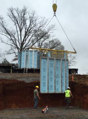 Precast concrete foundation walls are lowered into place at the site by crane. 