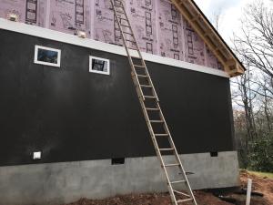 Extruded polystyrene (XPS) rigid foam is taped at the seams to provides a continuous air and weather-resistant barrier so no house wrap is needed; it also provides a continuous layer of insulation.