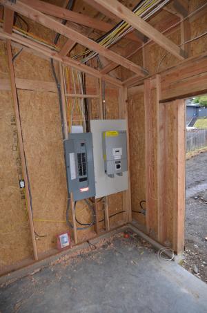Wall space is provided next to the electrical panel in the garage for the home’s photovoltaics system.