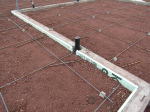 Two inches (R-10) of rigid foam line the interior of the perimeter footing walls before the post-tensioned slab is poured.