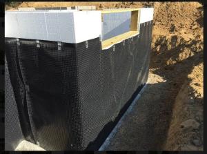 A dimpled plastic water barrier protects the insulated concrete form basement walls and carries any ground water down the walls to the footing drain to minimize the opportunity for water intrusion and frost heave.