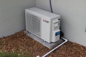 The high-efficiency mini-split heat pump provides cooling and heating; a drain pipe carries condensate away to a location that meets local code requirements.