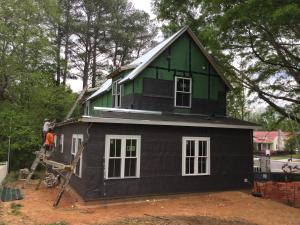 The builder installed a rain screen product that provides an air gap and drainage plane between the coated OSB sheathing and the cladding; the fabric layer folded over the bottom edge forms an insect screen. 