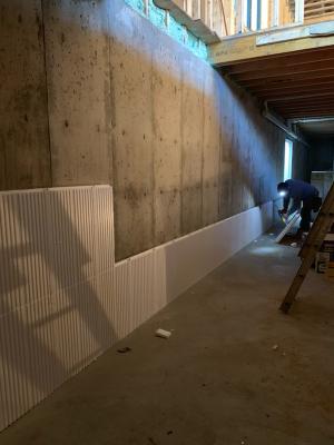 Right – Construction adhesive is applied to the rigid foam panels that will be installed on the interior basement walls.