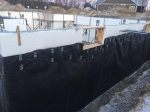 Right - A dimpled-plastic geotextile mat covers the below-grade insulated concrete form (ICF) foundation to help keep water out of the foundation and to reduce hydrostatic pressure on the foundation during freeze-thaw cycles in winter.