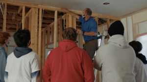 Right – An instructor shows students how to caulk the top plates of interior walls. 