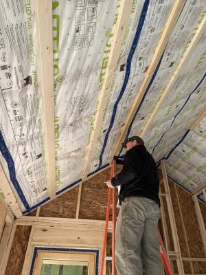 Horizontal furring strips are installed over a taped smart membrane that serves as an air and vapor barrier and holds in insulation; the furring strips will provide a nailing surface for tongue-and-groove wood porch ceiling cladding.