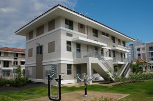 A resilient multifamily building in Puerto Rico constructed of concrete on a raised slab foundation with a hip roof design for wind resistance and deep overhangs and permanent awnings to keep sun and rain off windows.